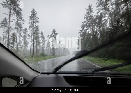 Fenêtre de voiture conduisant sur la route pendant la pluie, regardant de l'intérieur de la voiture vers l'extérieur Banque D'Images