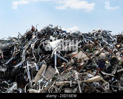 Ferraille sur un gros tas devant le ciel. Énorme pile de vieilles pièces métalliques. Recyclage de déchets industriels. Junkyard avec pièces en acier jetées. Banque D'Images