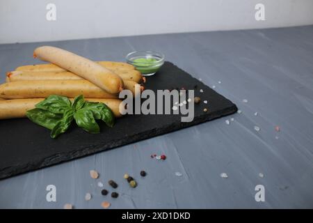 Délicieuses saucisses végétariennes ou végétaliennes avec du sel, des épices et des herbes sur un fond de béton foncé. Banque D'Images