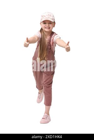 Mignonne petite fille montrant les pouces vers le haut tout en dansant sur fond blanc Banque D'Images