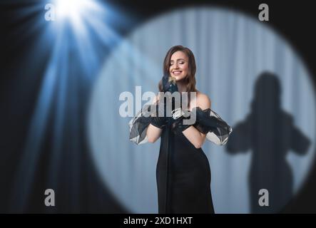 Belle chanteuse jouant sous les projecteurs sur scène Banque D'Images