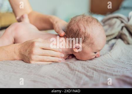 La peau du nouveau-né pèle. Maman utilise des produits pour la peau et des massages pour soigner et apaiser la peau délicate du bébé, assurant confort et promotion Banque D'Images