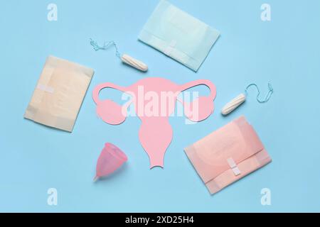 Composition avec utérus en papier et produits d'hygiène féminine sur fond de couleur Banque D'Images