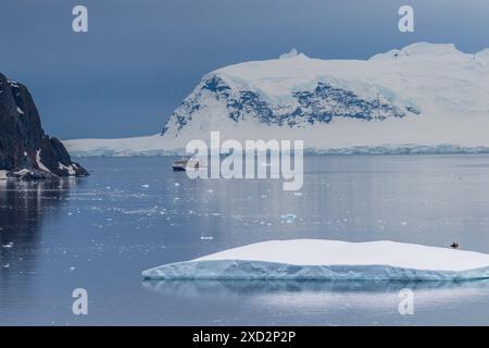 Île de Danco, péninsule Antarctique - 31 janvier 2024. Perspectives au-dessus des eaux antarctiques près de l'île de Danco, tandis que les touristes naviguent autour de Zodiacs et un bateau de croisière Antarctique passe par là. Banque D'Images