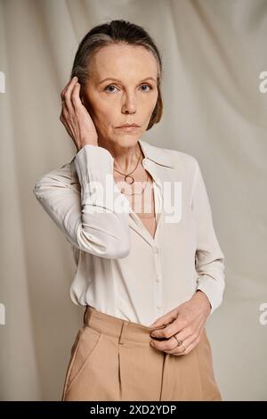 Femme mature en chemise blanche et pantalon bronzé avec grâce et calme. Banque D'Images