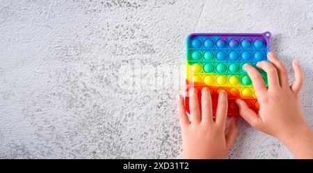 Vue de dessus de jouet sensoriel anti-stress arc-en-ciel fidget pousser sur fond de pierre Banque D'Images