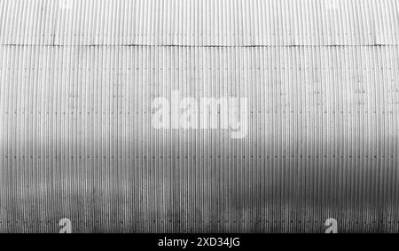 Mur métallique strié courbé brillant d'un bâtiment de stockage, texture de fond d'architecture industrielle moderne, photo en noir et blanc Banque D'Images