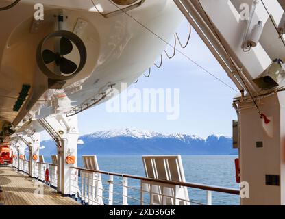 Vue de dessous d'un canot de sauvetage monté sur un grand navire de croisière. Montagnes enneigées au loin. Alaska. Banque D'Images