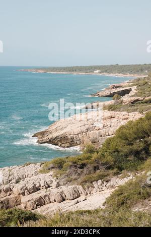 Une scène tranquille d'une plage isolée avec des eaux claires, avec une femme bronzant sur la côte immaculée, entourée par une nature intacte Banque D'Images