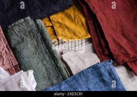 Vue de dessus d'une collection de serviettes textiles de différentes couleurs, soigneusement pliées et disposées dans un style de pose à plat, présentant une variété de textures de tissu. Banque D'Images