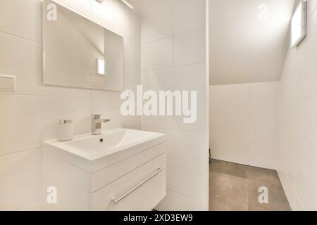 Une salle de bain blanche avec lavabo et miroir au-dessus de l'évier n'est pas en usage, mais il est très propre Banque D'Images