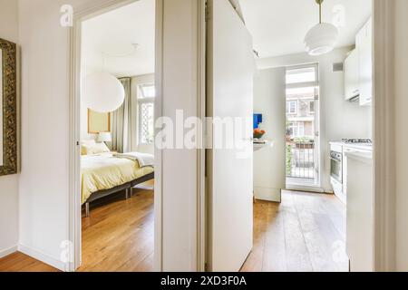 Une vue accueillante sur une chambre lumineuse et moderne à travers une porte ouverte, mettant en valeur un design intérieur de bon goût avec parquet et lumière naturelle Banque D'Images