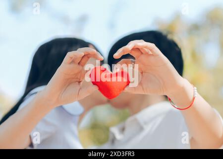 Les couples affichent des symboles en forme de cœur ensemble pour montrer leur amour et leur amitié les uns pour les autres sur leur grand jour. fabrication du symbole de coeur en forme de main à ex Banque D'Images