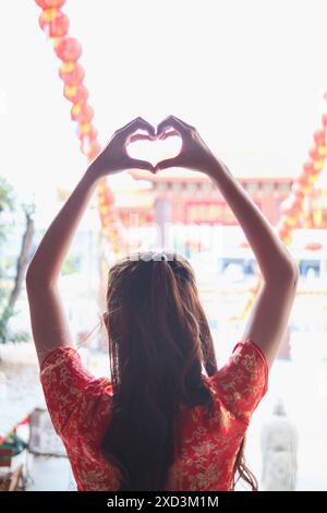 Une jeune femme lève les mains pour faire un symbole de cœur signifiant amour et amitié. Concept de mains ​​using pour faire un symbole de coeur représente la moyenne Banque D'Images