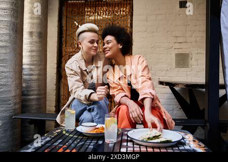 Deux femmes assises étroitement ensemble à une table, engagées dans la conversation et la connexion. Banque D'Images