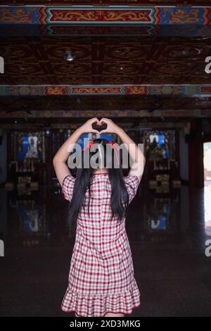 Une jeune femme lève les mains pour faire un symbole de cœur signifiant amour et amitié. Concept de mains ​​using pour faire un symbole de coeur représente la moyenne Banque D'Images