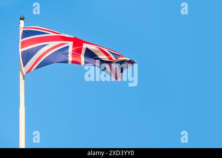 Drapeau du Royaume-Uni imprégné d'histoire, vagues contre un ciel bleu clair, esprit durable du Royaume-Uni et riche héritage, Union Jack Banque D'Images