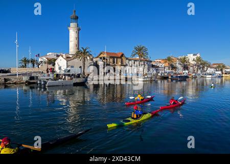 Passage de kayaks de mer devant le phare à l'entrée du port du Grau-du-Roi | passage de kayaks de mer devant le phare à l'entrée du port du Grau-du-Roi. Occitanie, France Banque D'Images