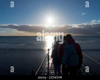 Groupe de visite sur une jetée au lever du soleil sur la mer sur le détroit de Magellan, Punta Arenas, Chili Banque D'Images