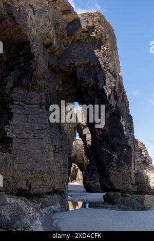 Formations naturelles d'arc rocheux sur une plage de sable avec un fond de ciel bleu. vue de la structure géologique côtière Banque D'Images