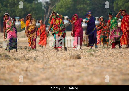 20 juin 2024, Dhaka, Dhaka, BANGLADESH : des femmes bangladaises transportent de l'eau potable après l'avoir récupérée d'une source d'eau douce, marchant un long chemin pour recueillir de l'eau potable dans la zone côtière de Khulna, au Bangladesh. Selon une étude de l’American Geophysical Union, l’élévation du niveau de la mer, qui affecte la disponibilité de l’eau potable, entraînera la migration d’environ 1,3 millions de personnes à travers le pays d’ici 2050. Une combinaison d'inondations dues aux marées, d'inondations dues aux ondes de tempête et d'intrusion d'eau salée entraîne une augmentation de la salinité dans les eaux souterraines et les eaux douces Banque D'Images