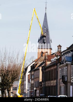 Haguenau, France - 20 mars 2024 : une grue de travail réparant le toit de l'église à Haguenau, France, région Alsace, présentant l'équipement de construction et les travailleurs dans le contexte du bâtiment historique Banque D'Images