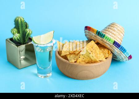 Chapeau de sombrero mexicain, cactus, chips de nachos et tequila sur fond bleu clair Banque D'Images