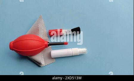 Photo de fournitures de nettoyage de caméra telles que ventilateur, brosse, chiffon en microfibre, jet d'eau sur un fond bleu Banque D'Images
