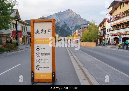 Banff, Alberta, Canada - septembre 28 2020 : signe de Share the Space sur l'avenue Banff en soirée d'automne. Cascade Mountain sur ciel rose dans le backgrou Banque D'Images