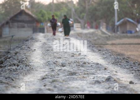 20 juin 2024, Dhaka, Dhaka, BANGLADESH : des femmes bangladaises transportent de l'eau potable après l'avoir récupérée d'une source d'eau douce, marchant un long chemin pour recueillir de l'eau potable dans la zone côtière de Khulna, au Bangladesh. Selon une étude de l’American Geophysical Union, l’élévation du niveau de la mer, qui affecte la disponibilité de l’eau potable, entraînera la migration d’environ 1,3 millions de personnes à travers le pays d’ici 2050. Une combinaison d'inondations dues aux marées, d'inondations dues aux ondes de tempête et d'intrusion d'eau salée entraîne une augmentation de la salinité dans les eaux souterraines et les eaux douces Banque D'Images