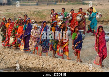 20 juin 2024, Dhaka, Dhaka, BANGLADESH : des femmes bangladaises transportent de l'eau potable après l'avoir récupérée d'une source d'eau douce, marchant un long chemin pour recueillir de l'eau potable dans la zone côtière de Khulna, au Bangladesh. Selon une étude de l’American Geophysical Union, l’élévation du niveau de la mer, qui affecte la disponibilité de l’eau potable, entraînera la migration d’environ 1,3 millions de personnes à travers le pays d’ici 2050. Une combinaison d'inondations dues aux marées, d'inondations dues aux ondes de tempête et d'intrusion d'eau salée entraîne une augmentation de la salinité dans les eaux souterraines et les eaux douces Banque D'Images