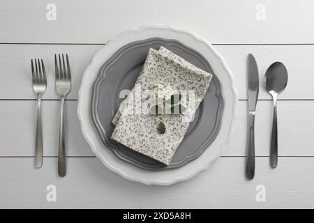 Cadre élégant avec couverts et assiettes sur table en bois blanc, pose à plat Banque D'Images