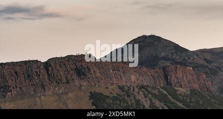 Vue panoramique sur les Salisbury Crags à Édimbourg avec les gens marchant sur le bord de la falaise et le sommet d'Arthurs assis derrière Banque D'Images