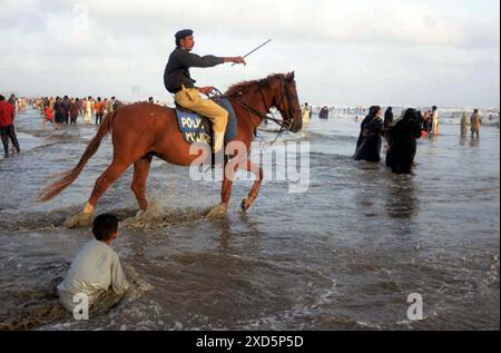 Les personnels de police patrouillant à cheval et dispersant les gens visitent Sea View Beach alors que l'interdiction a été imposée de se baigner dans la mer en raison des conditions difficiles de la mer, dans la zone de Clifton à Karachi le jeudi 20 juin 2024. Banque D'Images