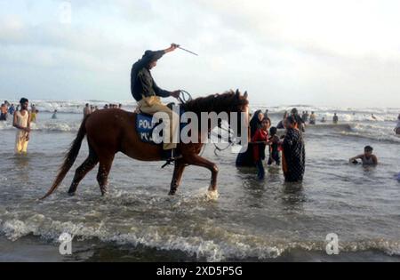 Les personnels de police patrouillant à cheval et dispersant les gens visitent Sea View Beach alors que l'interdiction a été imposée de se baigner dans la mer en raison des conditions difficiles de la mer, dans la zone de Clifton à Karachi le jeudi 20 juin 2024. Banque D'Images