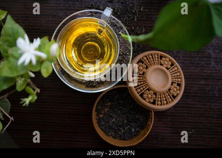 Thé vert bio avec fleur de jasmin et thé au jasmin avec feuilles séchées sur tasse à thé Banque D'Images