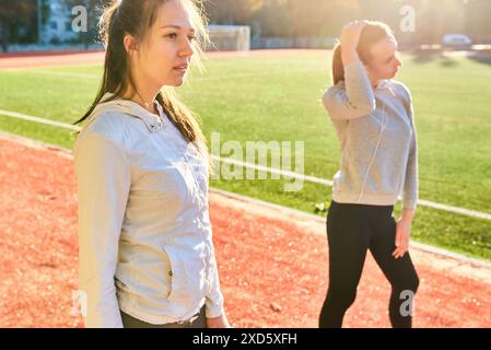 Deux filles en vêtements de sport posant au stade.Portrait de deux amies sportives au stade.Sport et vie saine. Banque D'Images