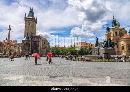 La place de la vieille ville de Prague, animée par les touristes, comprend l'ancien hôtel de ville, le mémorial Jan Hus et l'église de Nicolas sous un ciel bleu vibrant. Banque D'Images