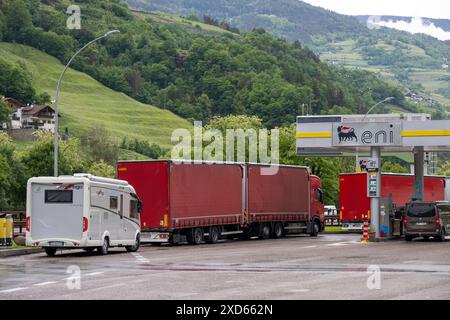 Véhicules, y compris un camping-car et des camions, ravitaillement en carburant à une station-service ENI sur l'autoroute A22 à Sudtirol, entourée de collines verdoyantes. Banque D'Images