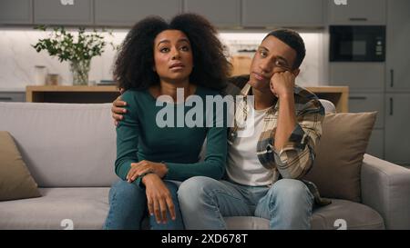 Agacé afro-américain ethnique épuisé jeune couple dérangé parents assis canapé pensant se sentir fatigué à propos bruyant petit garçon enfant hyperactif Banque D'Images