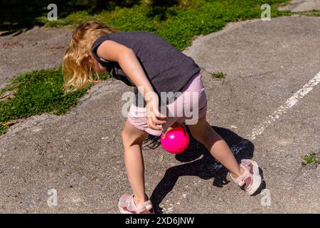 Jeune fille jouant avec une balle rose un jour ensoleillé Banque D'Images