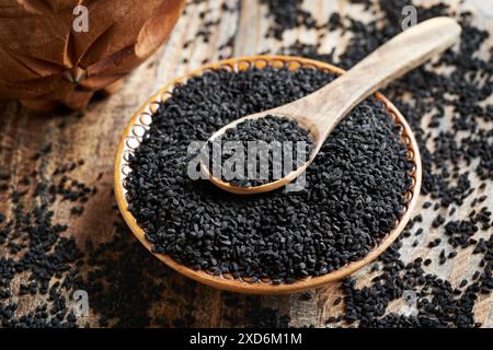 Cumin noir ou graines de Nigella sativa dans un bol avec une cuillère en bois Banque D'Images