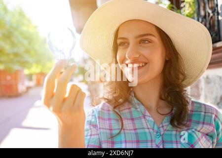 Une femme tenant et montrant une ampoule incandescente. Concept d'inspiration et de créativité, comme l'ampoule est souvent associée à des idées et innovati Banque D'Images