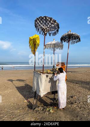 Canggu, île de Bali, Indonésie - 19 mai 2022 : femme balinaise exécutant le rituel traditionnel d'offrir aux dieux sur la plage, le matin balinais quotidien R Banque D'Images