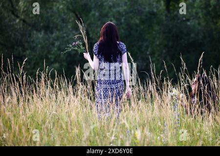 Cracovie, Pologne. 20 juin 2024. Une jeune fille cueille des plantes sauvages tout en célébrant le solstice d'été pendant la 'nuit de Kupala' près de la butte de Krakus à Cracovie, en Pologne, le 20 juin 2024. Le KupaÅ‚une nuit est la fête des vieux slaves tombant sur la nuit la plus courte de l'année. Au cours de cette nuit, des rituels ont été exécutés tels que la cueillette et la fabrication de couronnes à partir d'herbes et de fleurs sauvages par des filles et des jeunes femmes, l'envoi de guirlandes sur l'eau, l'allumage de feux, la danse, le chant et le saut par-dessus le feu. (Crédit image : © Beata Zawrzel/ZUMA Press Wire) USAGE ÉDITORIAL SEULEMENT! Non destiné à UN USAGE commercial ! Banque D'Images