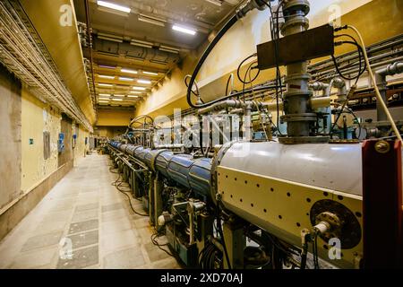 Grand tube métallique d'accélérateur de particules avec tuyaux connectés. Ancien bâtiment de laboratoire physique avec équipement synchrophasotron Banque D'Images