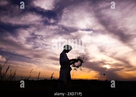 Cracovie, Pologne. 20 juin 2024. Une fille cueille des plantes sauvages tout en célébrant le solstice d'été pendant la 'Kupala Night' près de la butte de Krakus. La nuit de Kupala est un jour férié ancien slave tombant sur la nuit la plus courte de l'année. Au cours de cette nuit, des rituels ont été exécutés tels que la cueillette et la fabrication de couronnes à partir d'herbes et de fleurs sauvages par des filles et des jeunes femmes, l'envoi de guirlandes sur l'eau, l'allumage de feux, la danse, le chant et le saut par-dessus le feu. (Crédit image : © Beata Zawrzel/ZUMA Press Wire) USAGE ÉDITORIAL SEULEMENT! Non destiné à UN USAGE commercial ! Banque D'Images