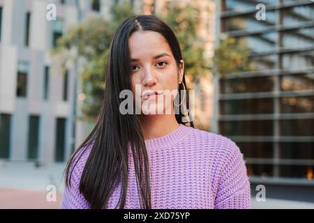 Un portrait d'une étudiante jeune Latina déterminée debout seule à l'extérieur, regardant vers l'avant avec une expression réfléchie, rayonnant de confiance et d'assurance de soi. Femme regardant sérieusement la caméra. Photo de haute qualité Banque D'Images