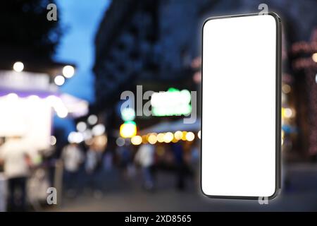 Téléphone portable avec écran vide contre la ville du soir. Espace pour le design Banque D'Images