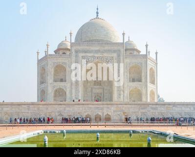 Foules colorées de visiteurs marchant le long du complexe Taj Mahal à Agra, en Inde. Vue imprenable sur le mausolée de marbre blanc sur fond de ciel bleu. Banque D'Images